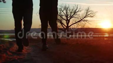 剪影两人在夕阳下的路上独自站在树上剪影。 运动的年轻人在大自然中奔跑